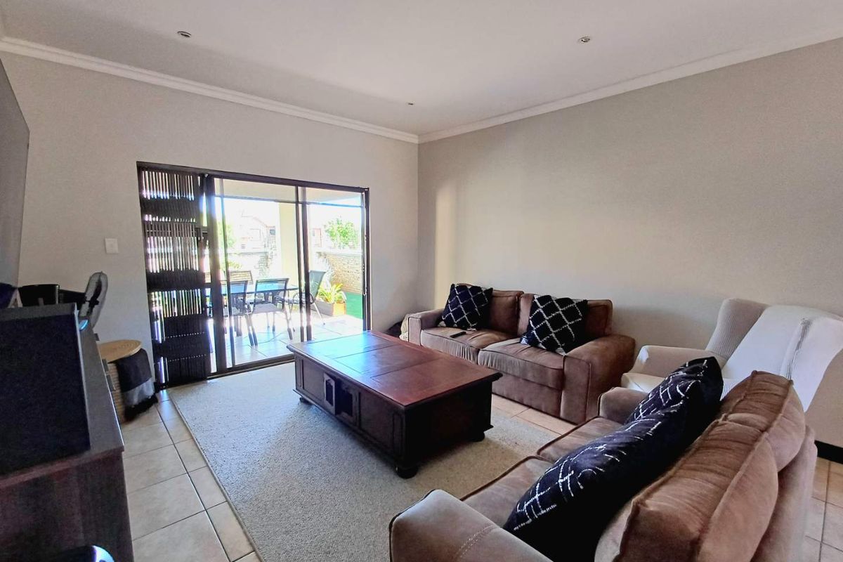 Spacious living room featuring tiled flooring, recessed ceiling lighting, and large sliding glass doors providing direct access to the outdoor patio area.