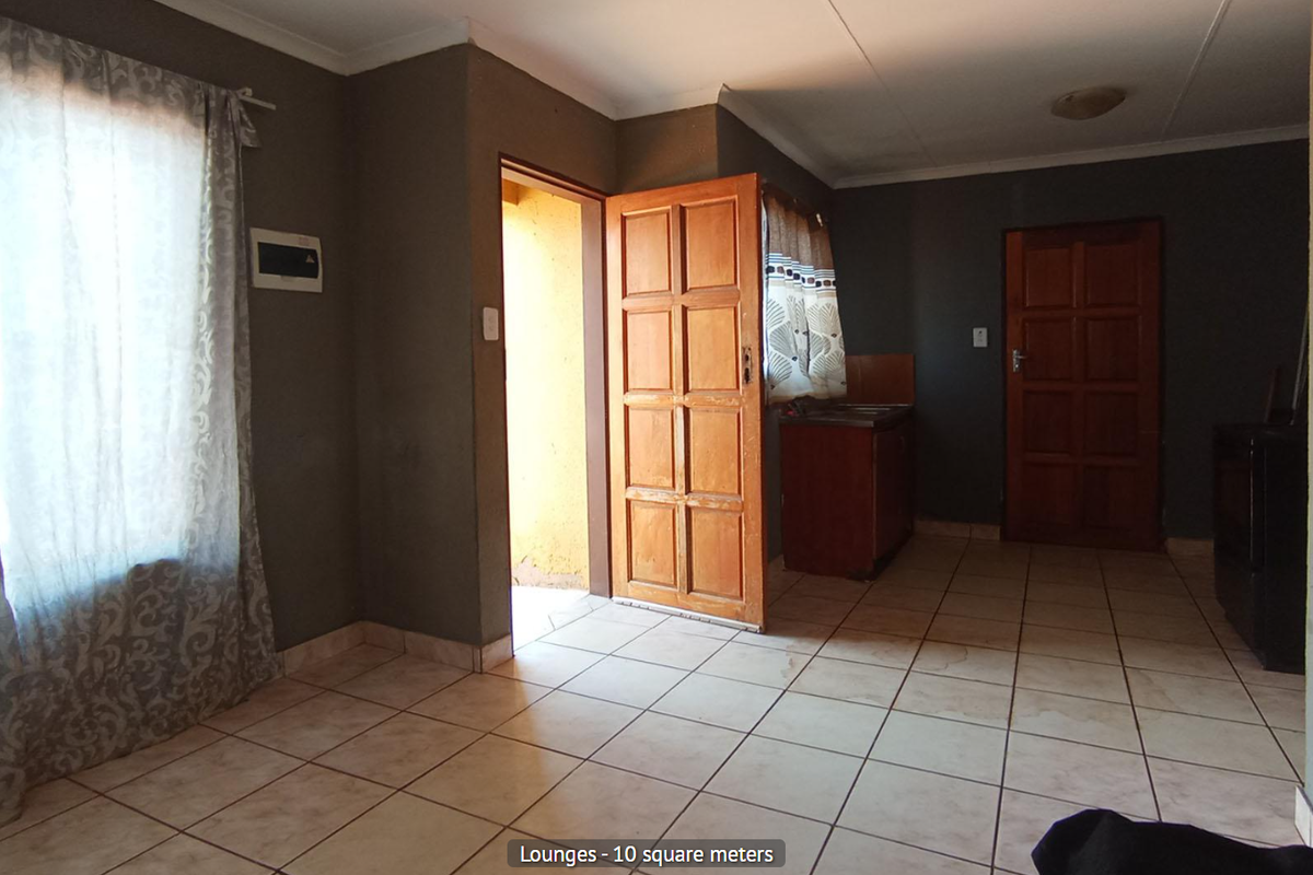 A compact living area featuring tiled flooring, dark painted walls, and direct access to an exterior doorway.