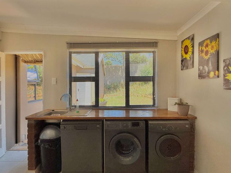 A functional laundry area featuring a built-in sink, wooden countertop, and brick base cabinetry with space for under-counter appliances.