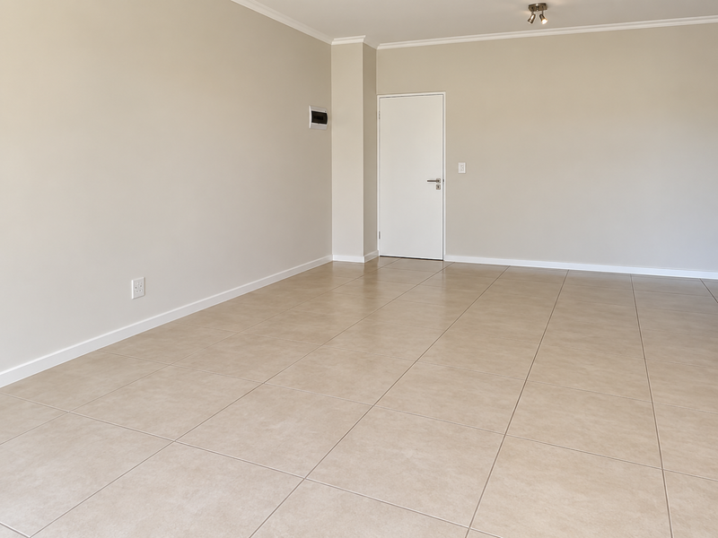 A bright, empty living room featuring neutral walls, tiled flooring, and clean architectural finishes, providing a versatile blank canvas for interior design.