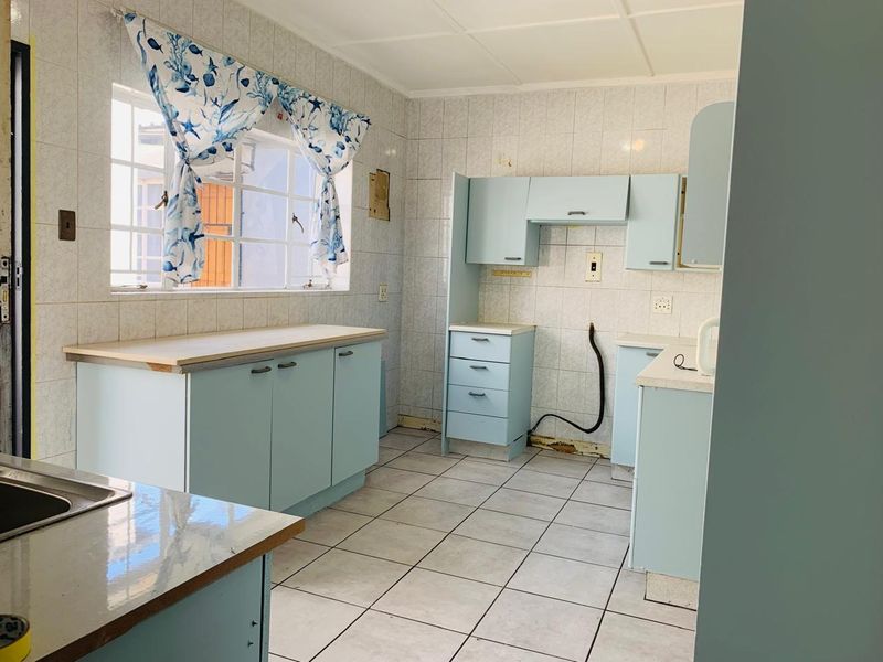 A dated kitchen featuring tiled walls and floors with light blue built-in cabinetry, offering a blank canvas for modern renovation and design updates.