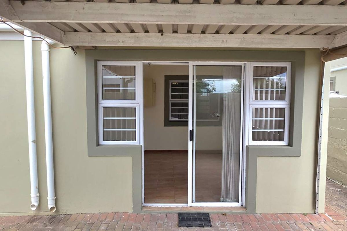 Rear exterior view of the townhouse featuring a covered patio area with sliding glass doors and paved courtyard.