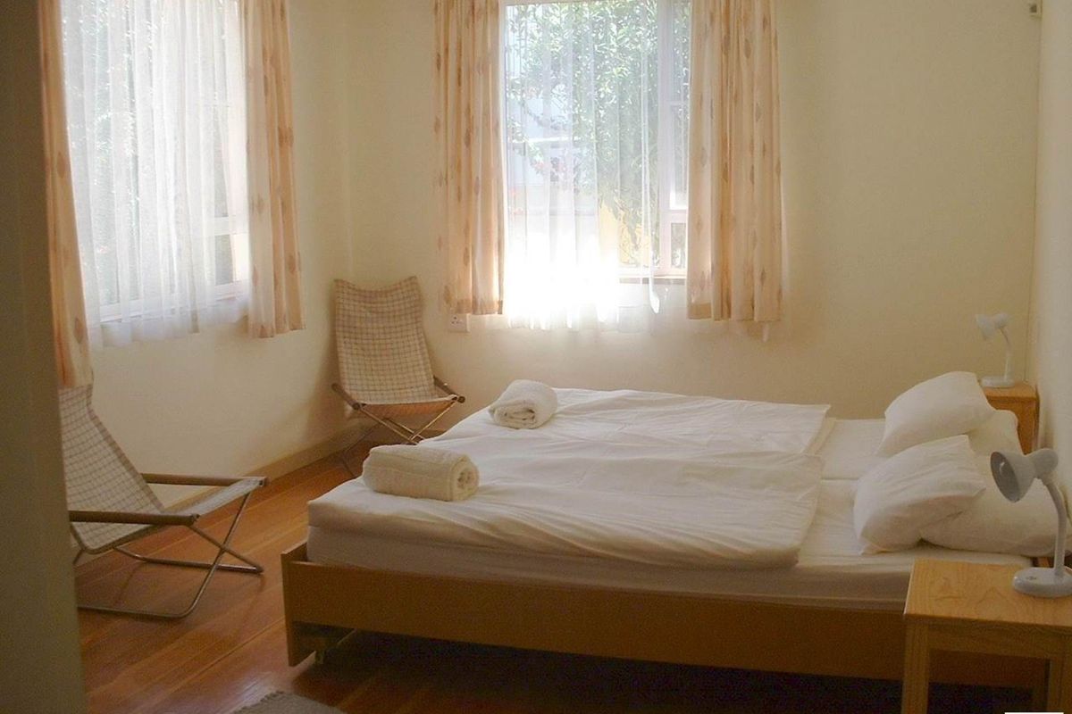 A simple bedroom featuring timber flooring and large windows that allow for natural light.