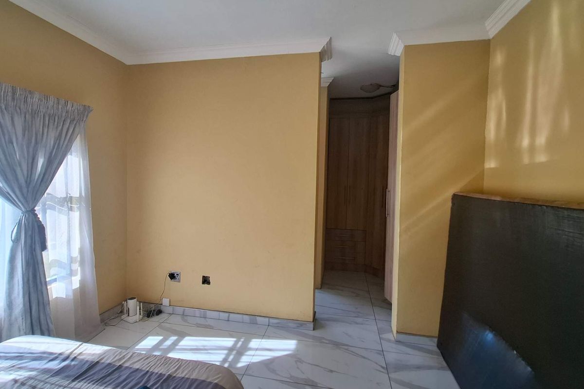 Bedroom featuring tiled flooring, built-in cupboards, and cornicing. The room requires minor maintenance to electrical fittings.