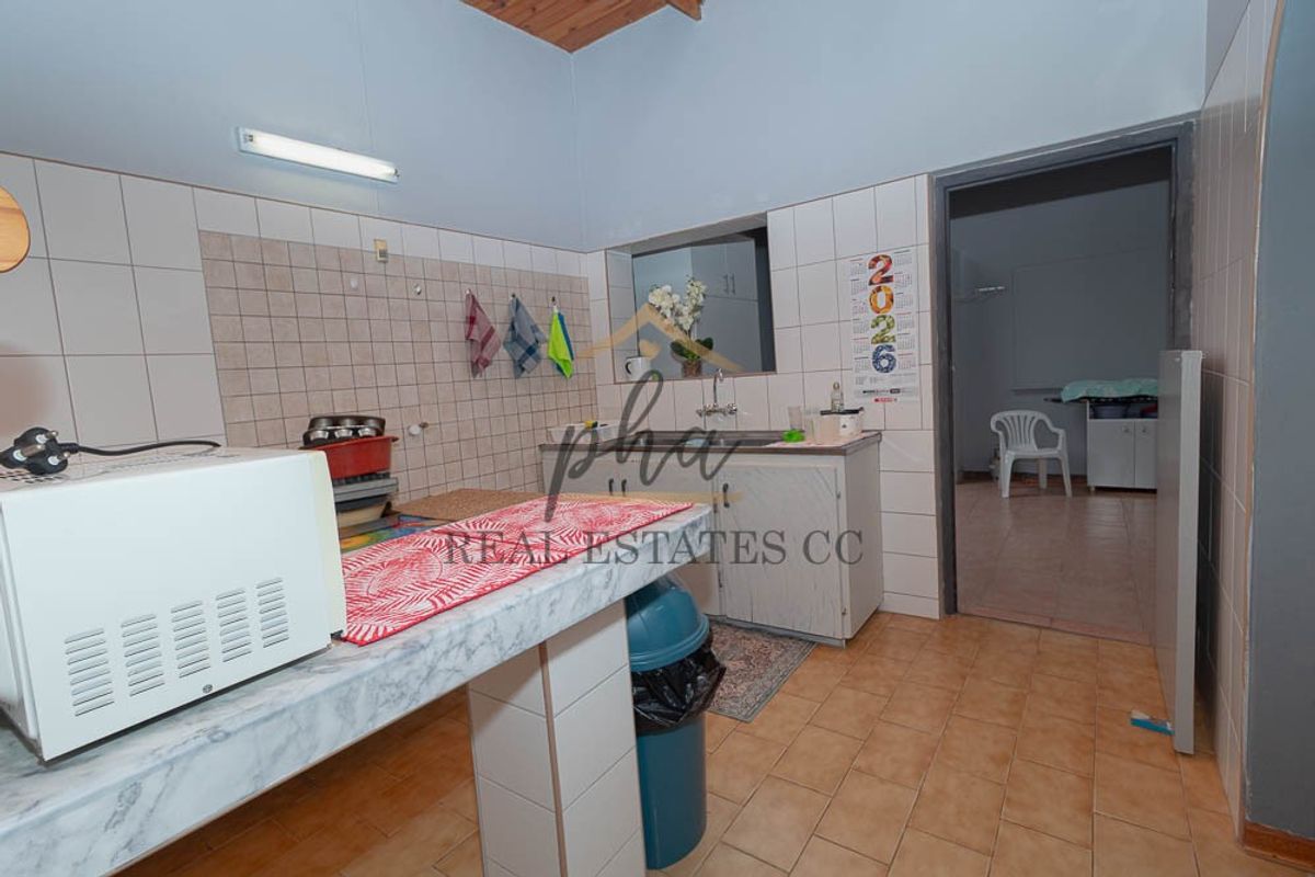 A functional kitchen area featuring tiled backsplash, built-in cabinetry, and tiled flooring, offering a practical space for culinary activities.