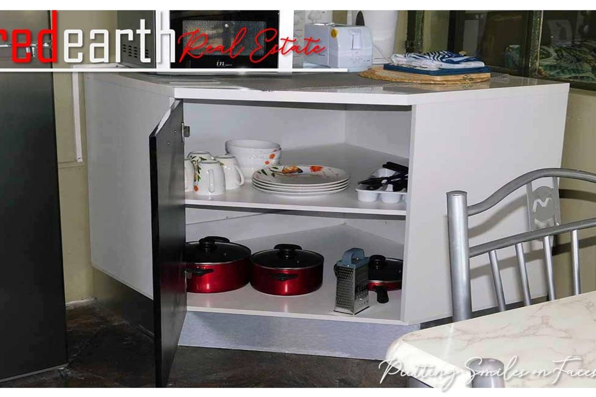 A close-up view of a white corner kitchen cabinet unit with open shelving, providing accessible storage for kitchenware.