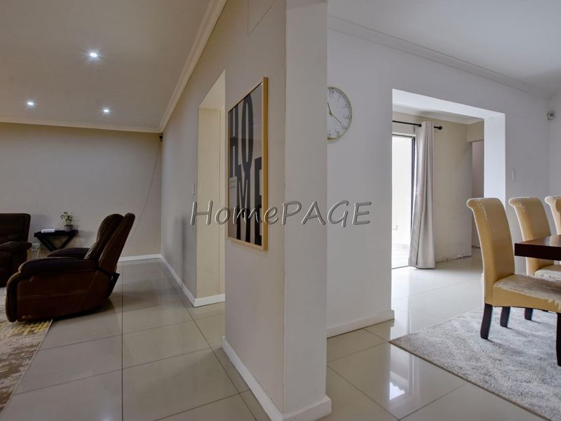 Open plan living and dining area featuring neutral tiled flooring, recessed downlighting, and a sliding door providing access to the exterior.