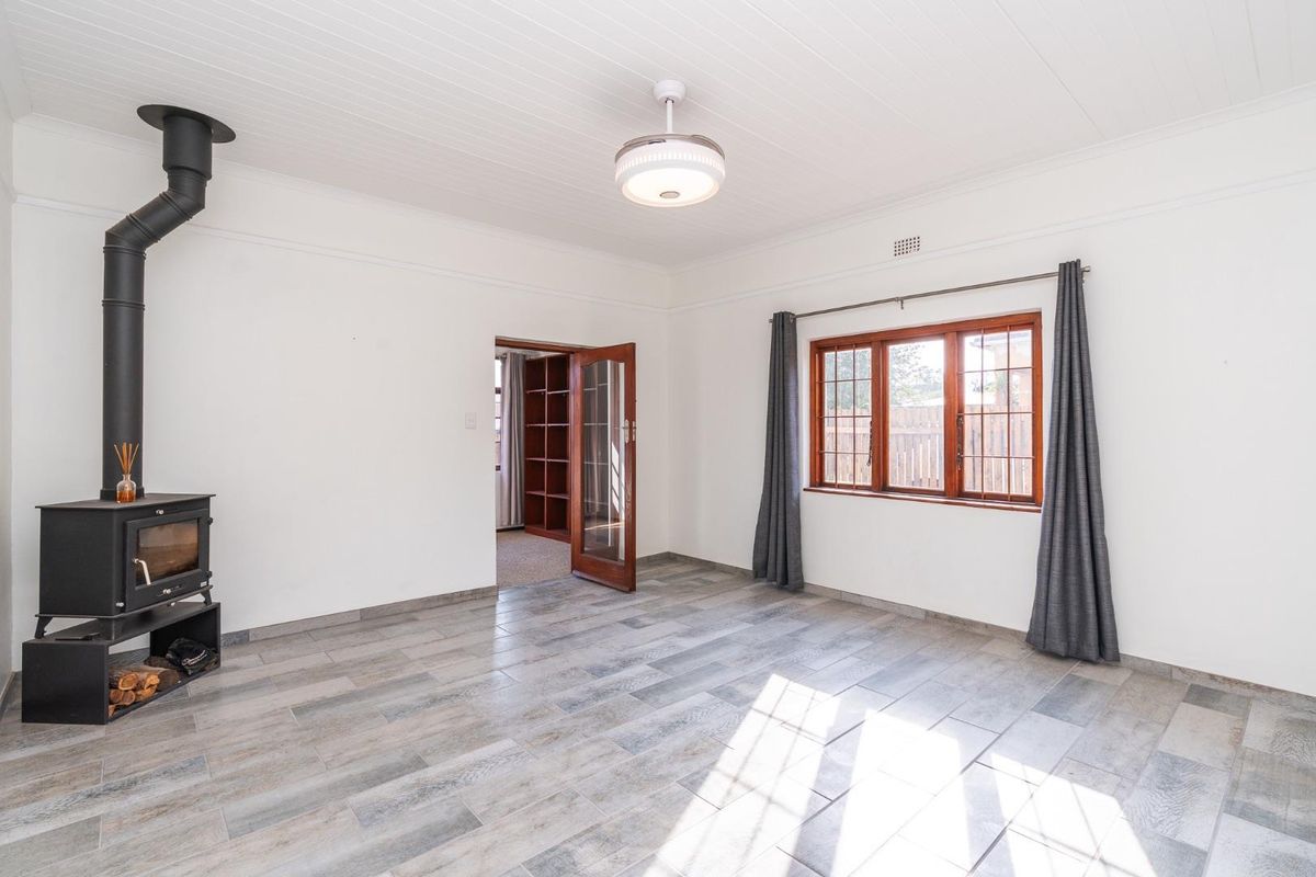 Bright living room featuring a wood-burning stove, tiled flooring, and timber-framed windows, offering a clean and neutral space ready for personalization.