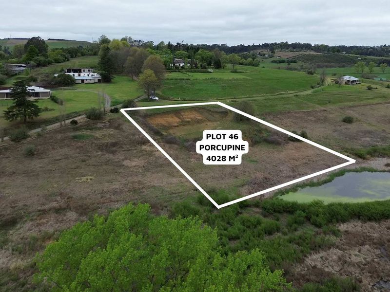 Aerial view of a 4028 square meter vacant residential plot featuring natural landscape and an adjacent pond.