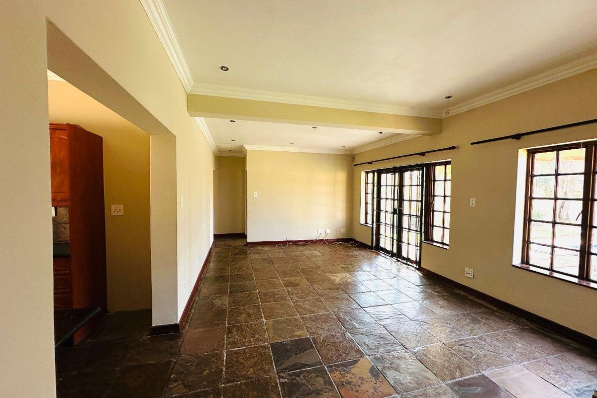 Spacious, empty living area featuring natural slate tile flooring, crown molding, and large sliding glass doors providing access to the exterior.