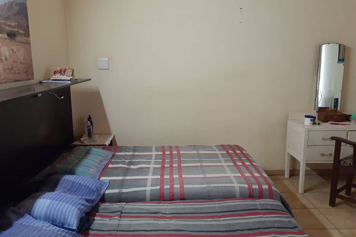 A functional bedroom featuring tiled flooring and neutral wall finishes, providing a simple and practical sleeping space.