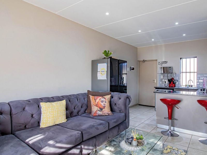 Open-plan living area featuring a modern kitchen with a breakfast bar, tiled flooring, and recessed ceiling lighting.