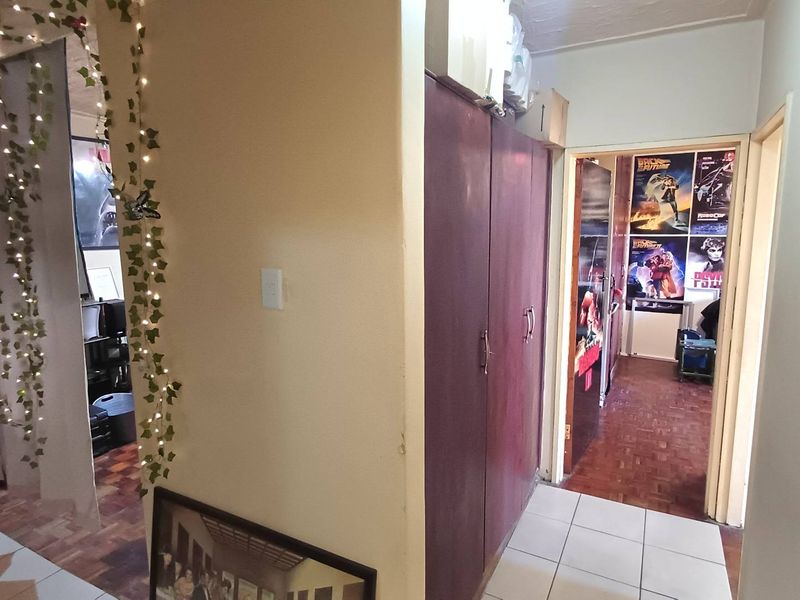 A functional hallway featuring built-in storage cupboards, parquet flooring, and tiled transition areas, connecting multiple rooms within the apartment.