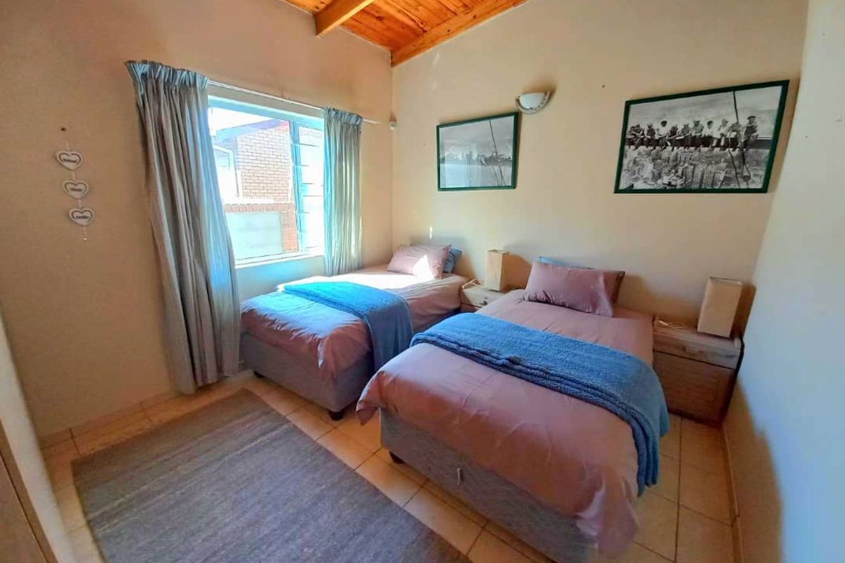 A bedroom featuring tiled flooring and a vaulted timber-paneled ceiling, providing a cozy and functional sleeping space.