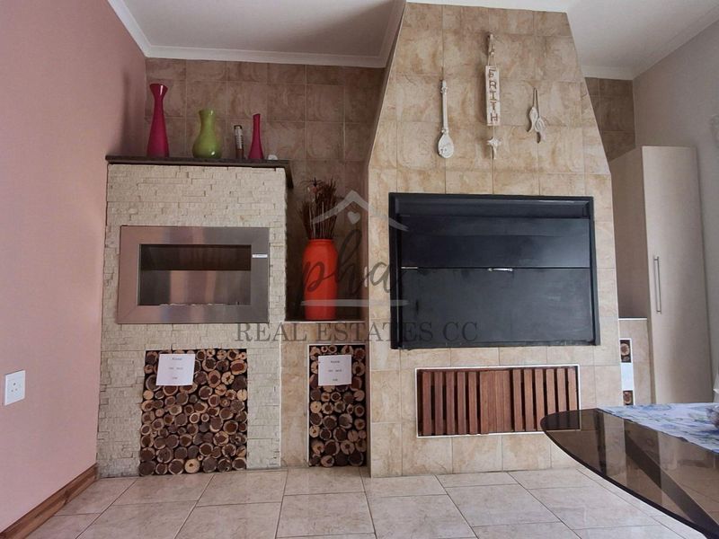 Living area featuring a large tiled built-in fireplace and integrated braai with stone cladding finishes.