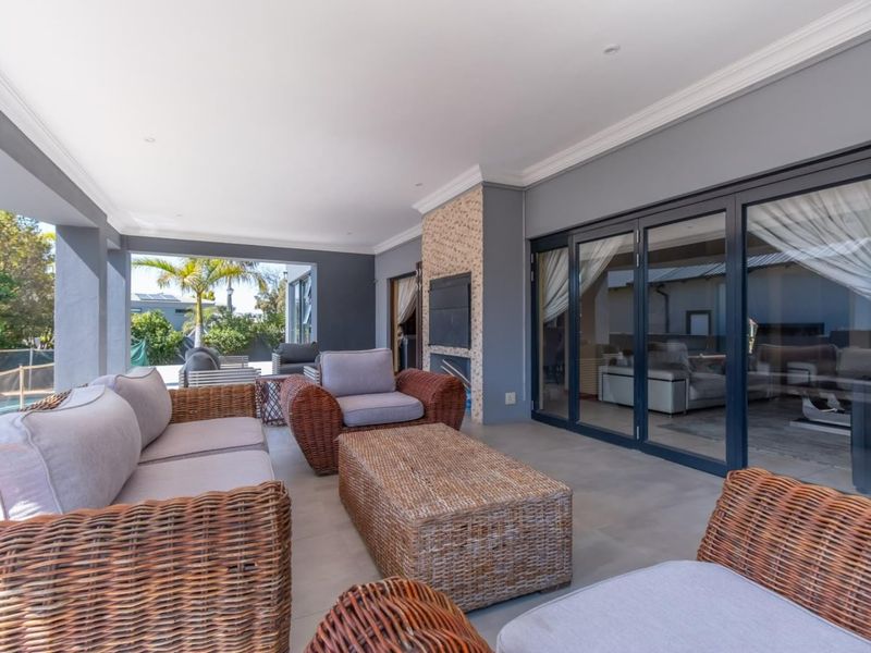 Spacious covered patio featuring tiled flooring, a built-in fireplace with stone cladding, and large sliding glass doors providing seamless indoor-outdoor flow.