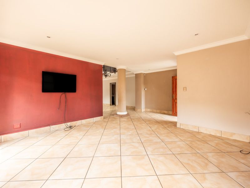 Spacious open-plan living area featuring tiled flooring, a central structural column, and recessed lighting, offering a versatile blank canvas for interior design.