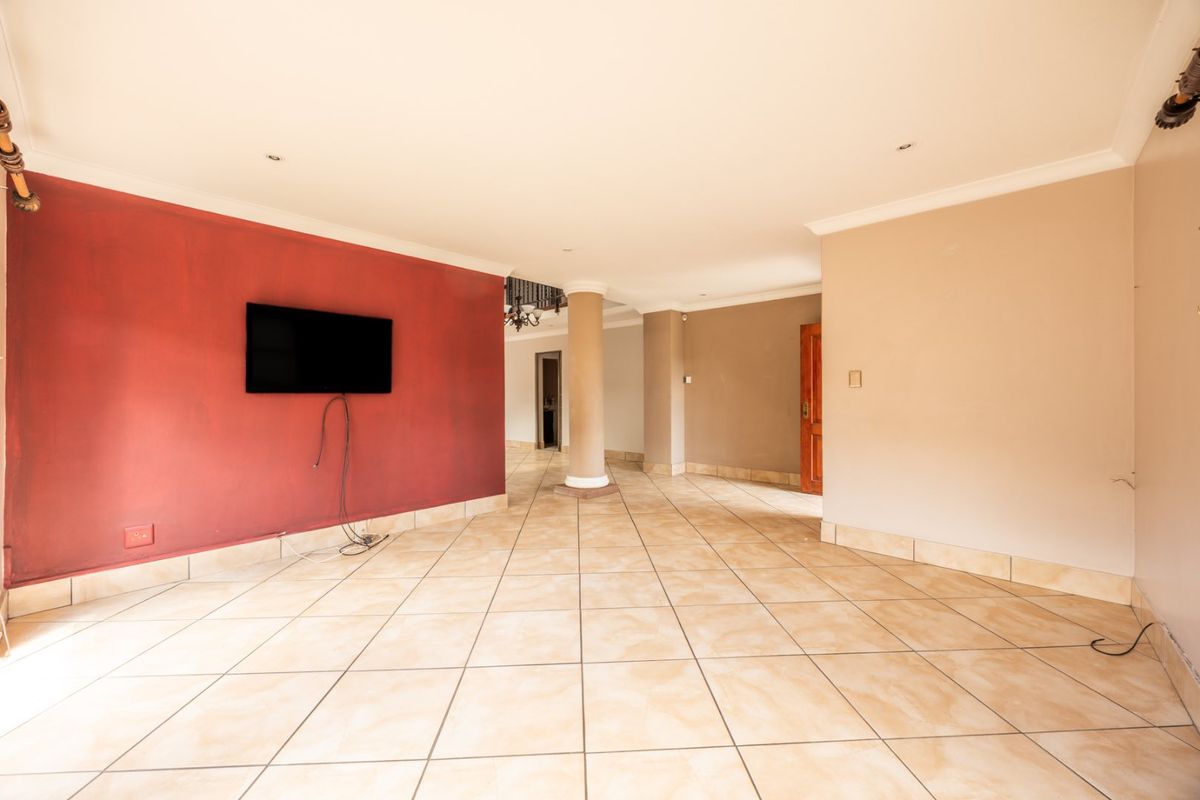 Spacious open-plan living area featuring tiled flooring, a central structural column, and recessed lighting, offering a versatile blank canvas for interior design.