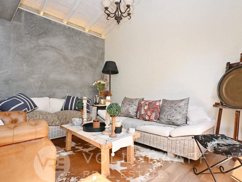 A cozy living room featuring a textured cement feature wall, exposed beam ceiling, and painted brick walls, creating a warm and inviting atmosphere.