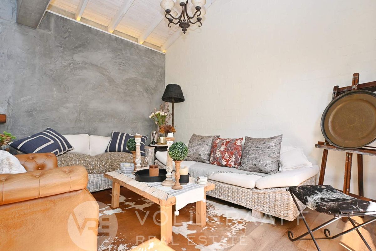 A cozy living room featuring a textured cement feature wall, exposed beam ceiling, and painted brick walls, creating a warm and inviting atmosphere.