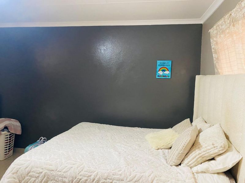 A bedroom featuring a dark accent wall and neutral finishes, providing a blank canvas for potential interior design updates.