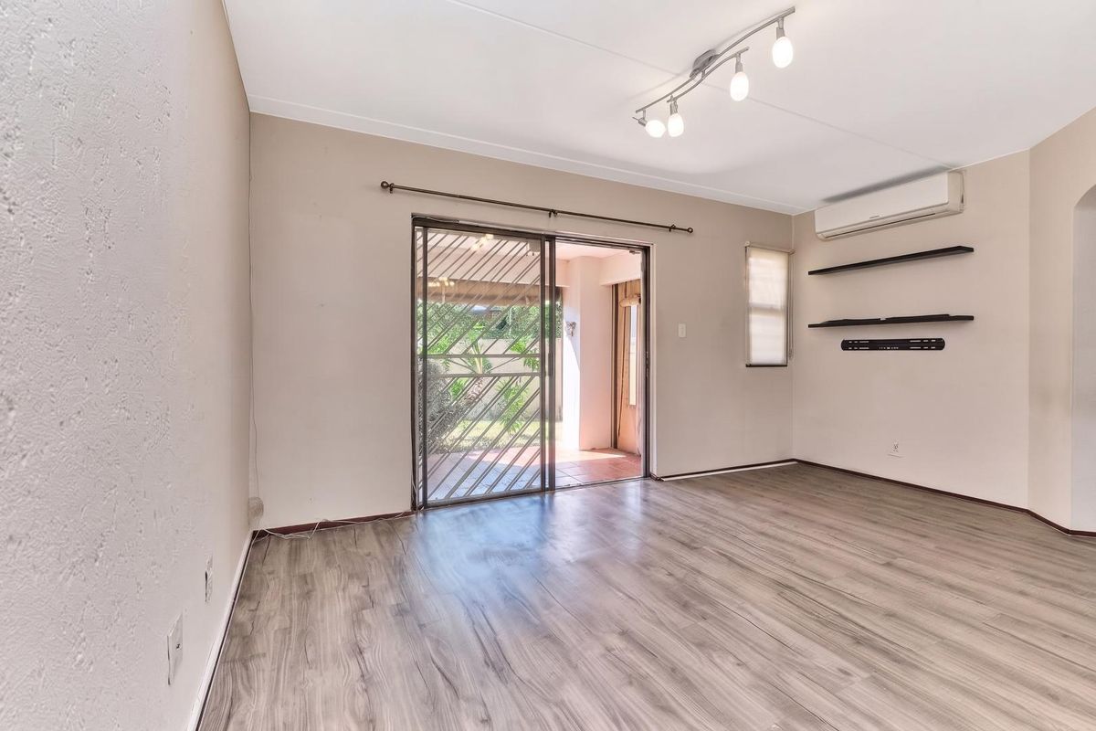 Bright and spacious living area featuring modern laminate flooring, split-system air conditioning, and direct access to an outdoor patio through a sliding glass door.
