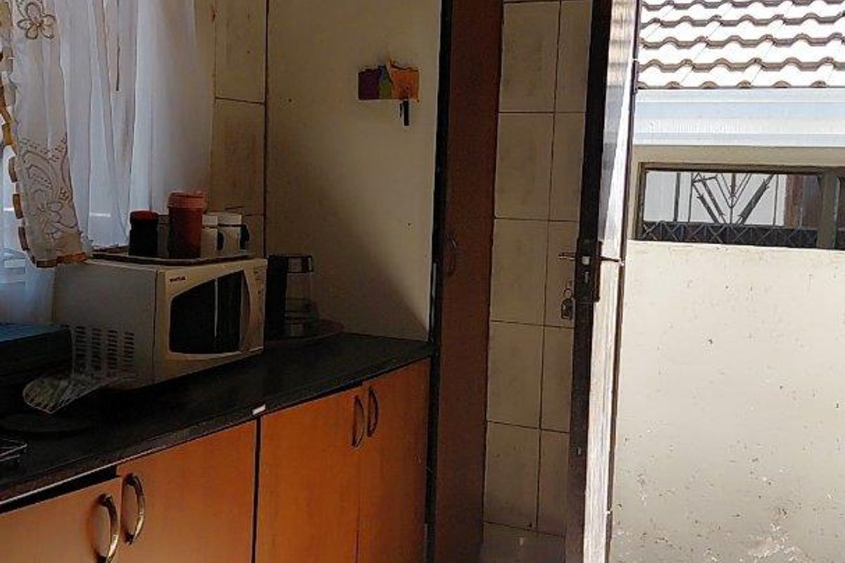 A functional kitchen area featuring built-in cabinetry, tiled surfaces, and direct access to an exterior space.