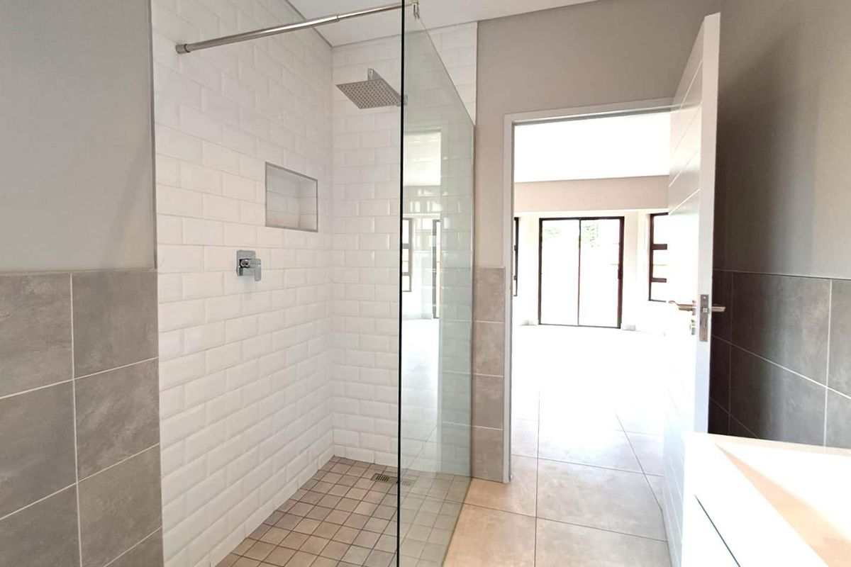 Modern bathroom featuring a walk-in shower with a glass screen, subway tile surround, and a built-in shower niche.