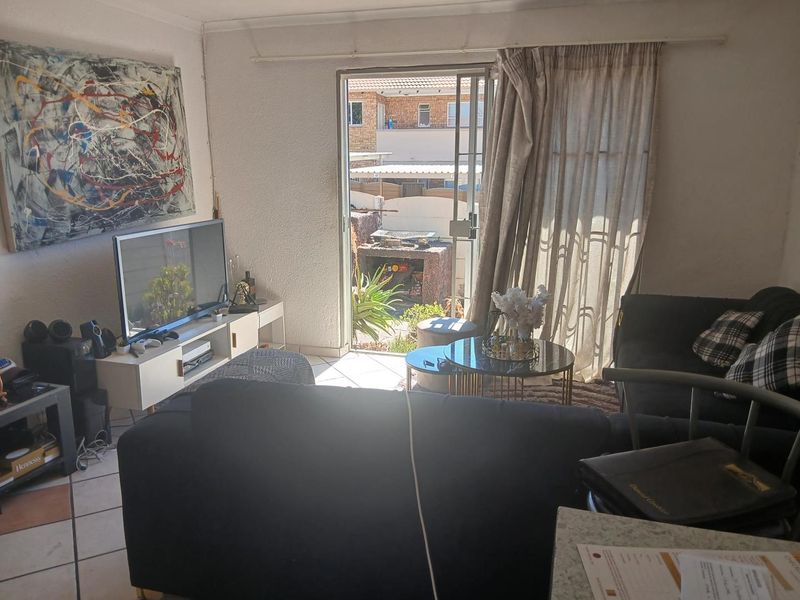 A living room featuring tiled flooring and a sliding glass door providing access to an outdoor patio area.