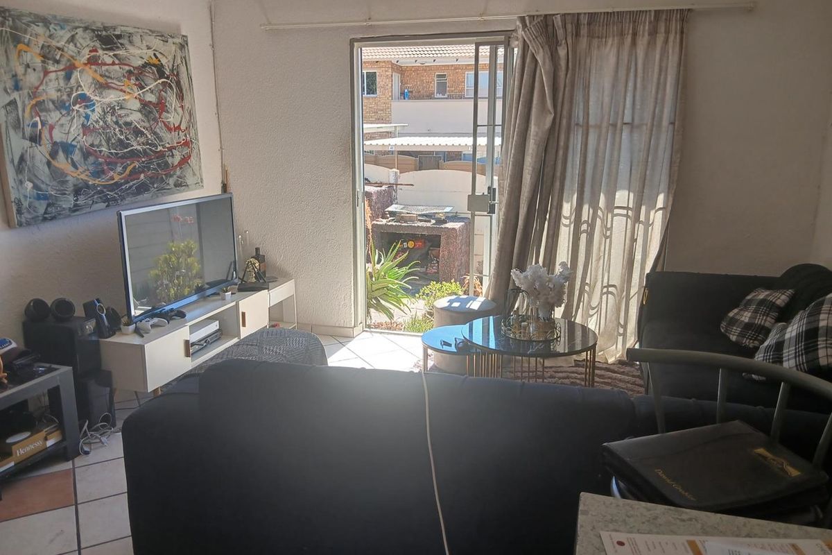 A living room featuring tiled flooring and a sliding glass door providing access to an outdoor patio area.
