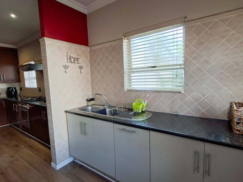 A functional kitchen featuring dark wood cabinetry, granite countertops, a tiled backsplash, and integrated appliances, with a separate prep area and sink.