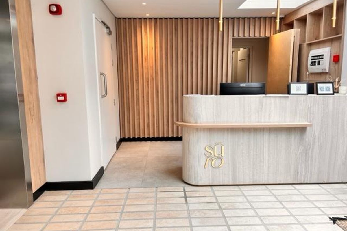 Modern apartment building entrance lobby featuring a stone-finish reception desk, timber slat wall paneling, and high-quality tiled flooring.