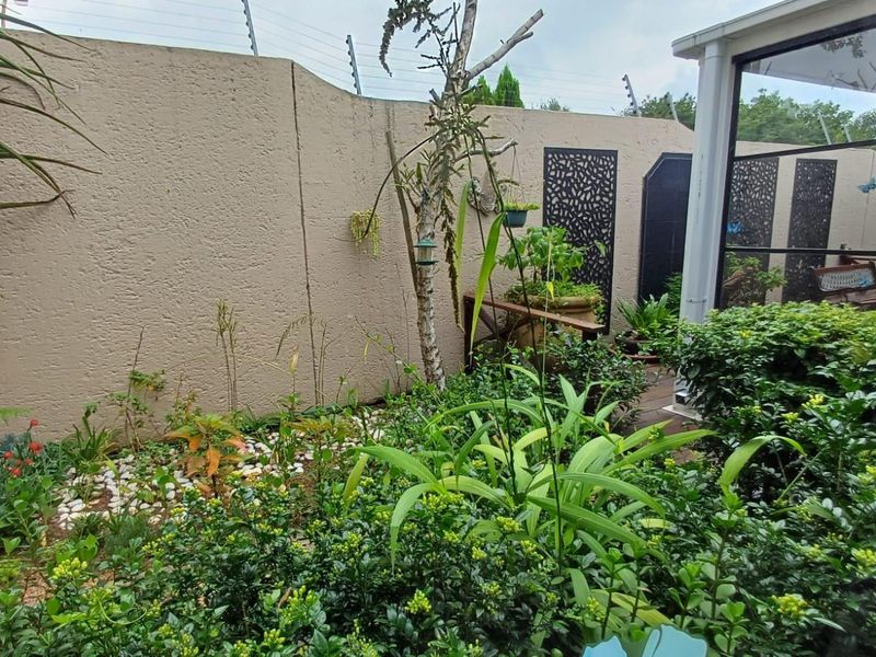 A private garden area featuring a perimeter wall with electric fencing, decorative privacy screens, and established landscaping.