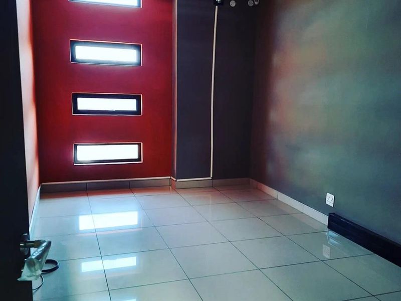 A clean, empty office space featuring modern tiled flooring, recessed ceiling lighting, and distinctive vertical accent windows.