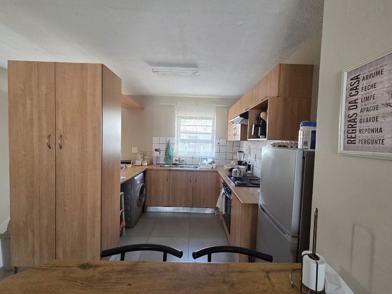 A functional kitchen featuring laminate cabinetry, built-in oven with hob, extractor fan, and tiled backsplash, offering a practical layout for daily use.