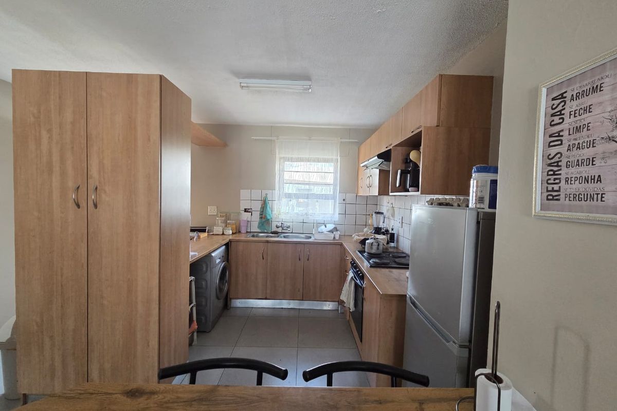 A functional kitchen featuring laminate cabinetry, built-in oven with hob, extractor fan, and tiled backsplash, offering a practical layout for daily use.