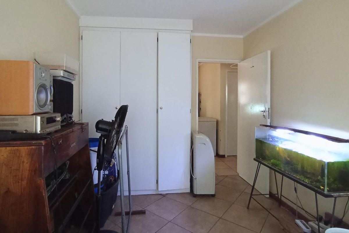 A bedroom featuring built-in cupboards and tiled flooring, providing a functional space with direct access to an adjacent hallway.