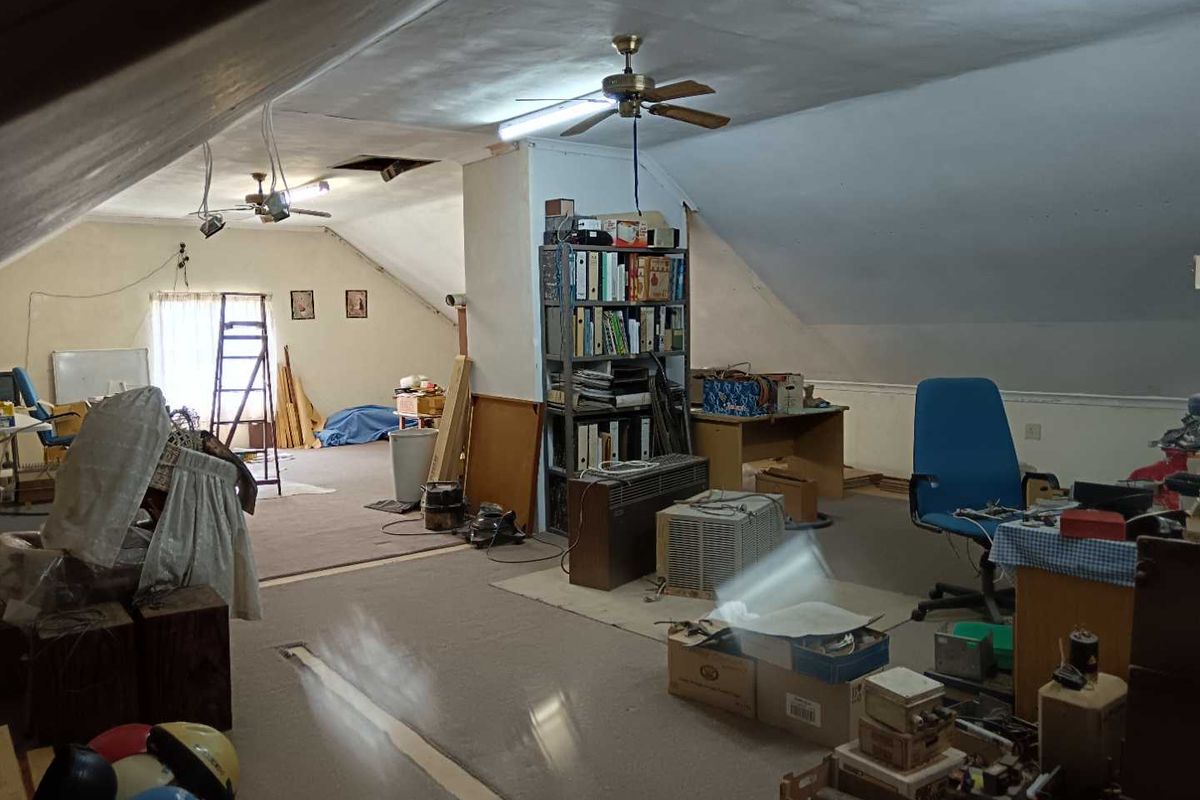 Spacious attic-style room with sloped ceilings, featuring exposed wiring and basic finishes, offering potential for conversion into a bedroom or home office.