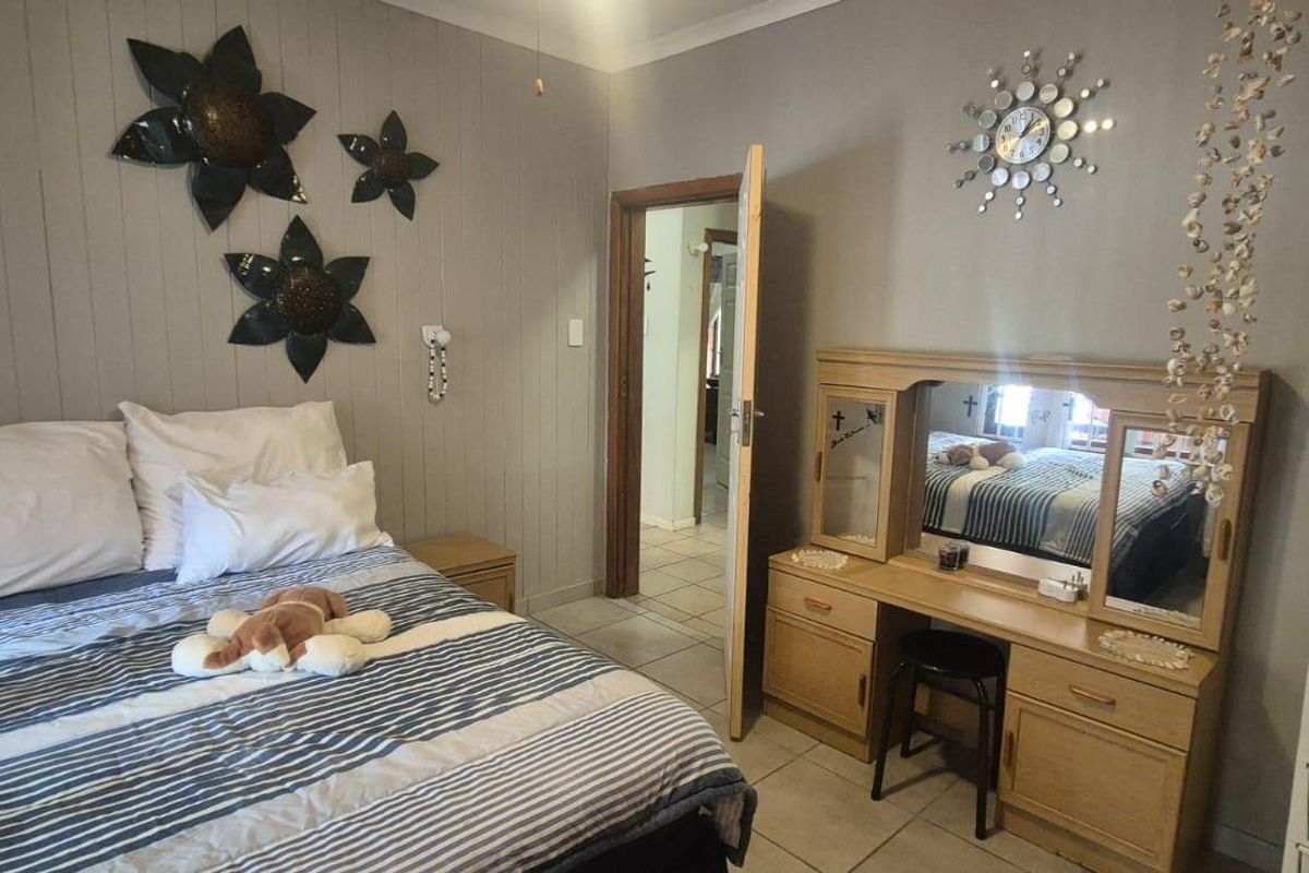 A bedroom featuring tiled flooring and vertical wall paneling, providing a functional space with direct access to the hallway.