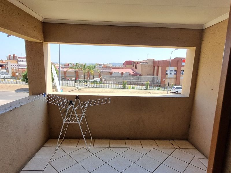 A covered balcony featuring tiled flooring and an open view of the surrounding neighborhood.