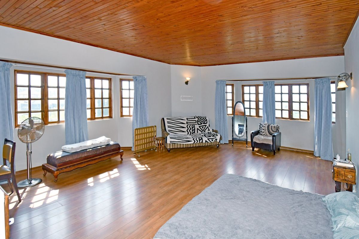 Spacious living room featuring warm timber ceilings, laminate flooring, and dual bay windows that provide ample natural light.
