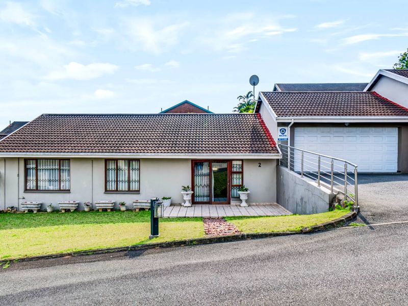 Front elevation of a townhouse featuring a tiled roof, paved driveway, and an integrated double garage with a secure entrance.