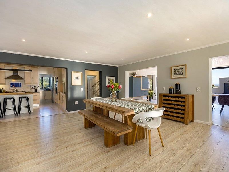 Spacious open-plan living and dining area featuring light laminate flooring, recessed lighting, and a modern kitchen with built-in cabinetry and integrated appliances.