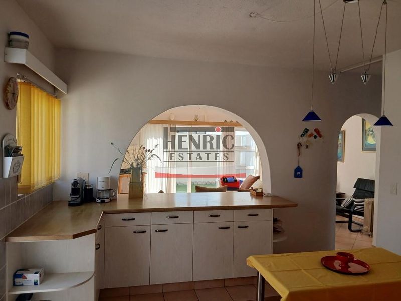 A functional kitchen featuring built-in cabinetry, laminate countertops, and a distinctive arched opening that connects to the adjacent living space.