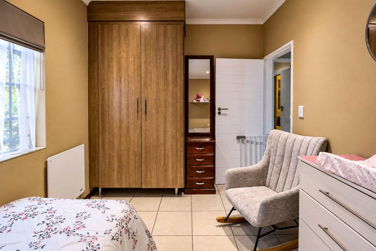 A well-maintained bedroom featuring neutral wall tones, tiled flooring, and a functional built-in wardrobe with wood-grain finish.