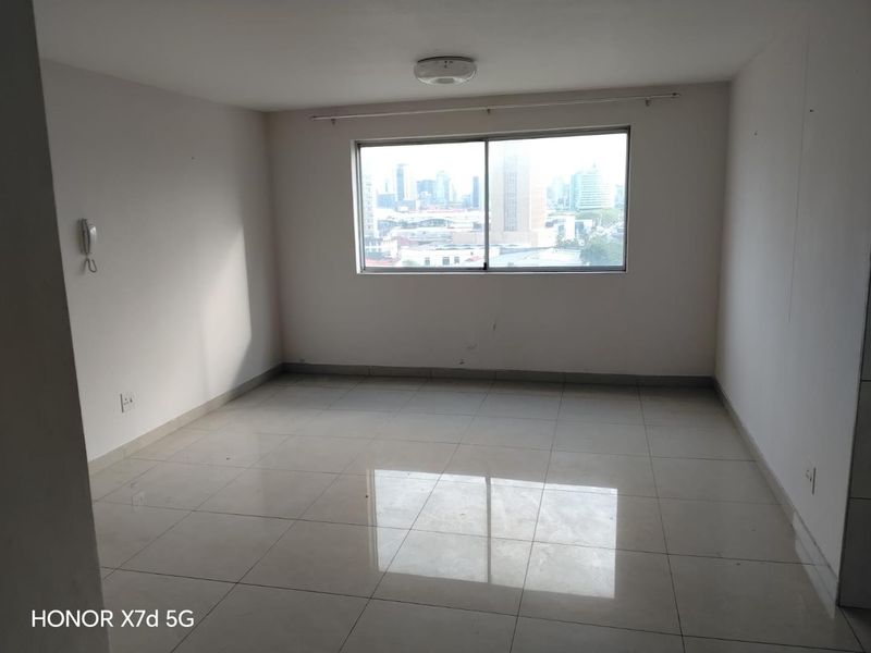 An empty bedroom featuring tiled flooring, a sliding window with city views, and an intercom system.