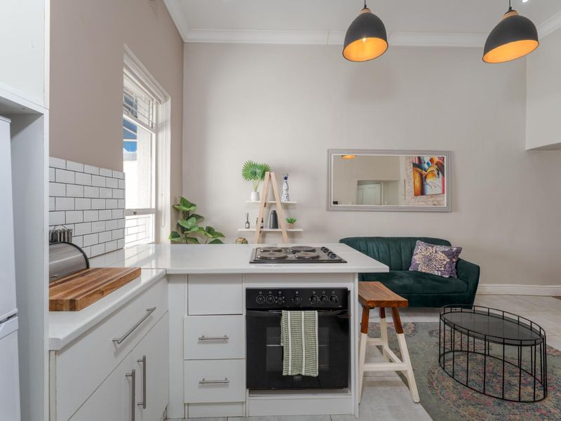 Open-plan living area featuring a modern kitchen with subway tile backsplash, built-in oven, gas hob, and quartz countertops, seamlessly integrated with the lounge space.