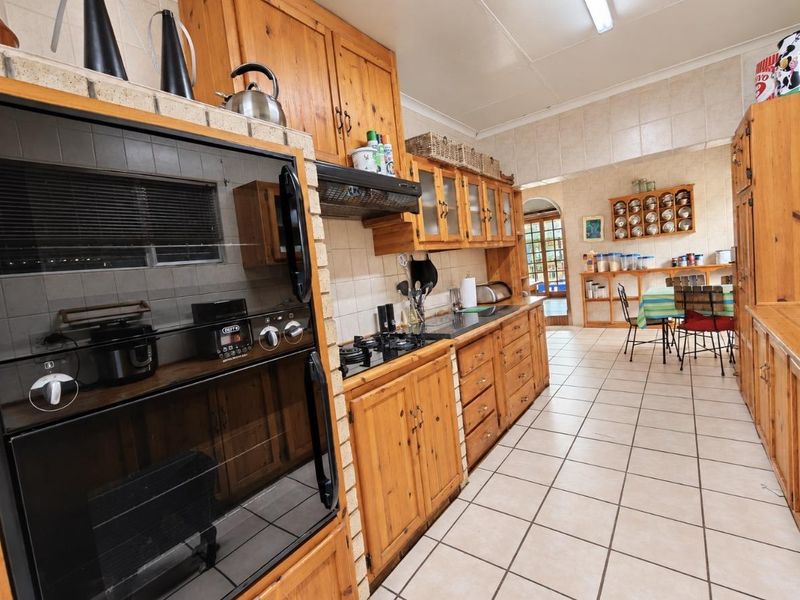 Spacious kitchen featuring extensive wooden cabinetry, built-in oven, gas hob, and tiled flooring, offering a functional layout with integrated storage and dining space.