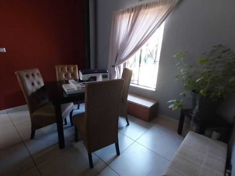 A dining area featuring tiled flooring and a window with security bars, providing a functional space for meals.