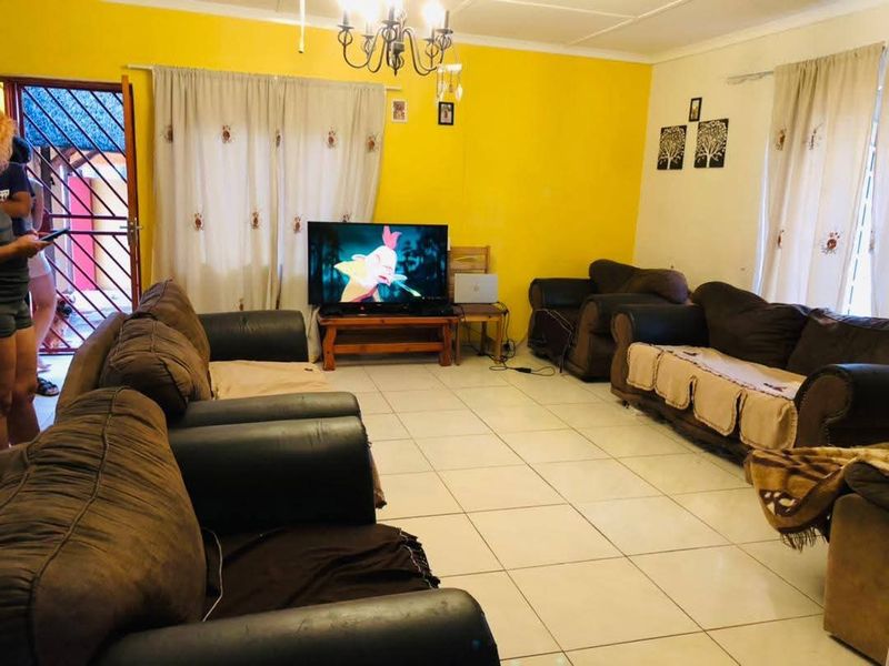 A living room featuring tiled flooring, bright yellow walls, and a security gate leading to the exterior.